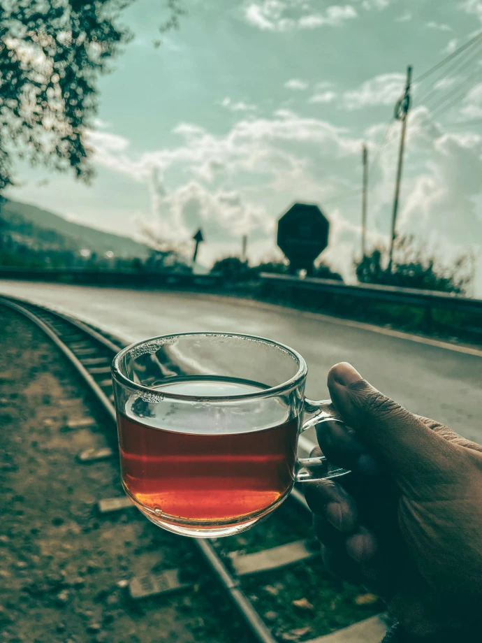 a person holding a glass of tea on a train track